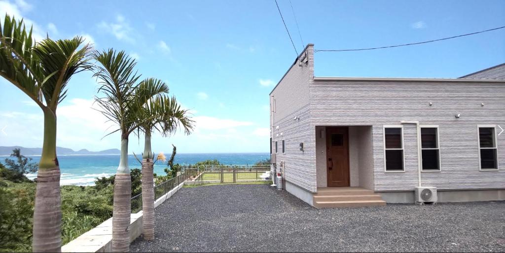 a white house with palm trees next to the ocean at Sol e Mar in Tatsugo