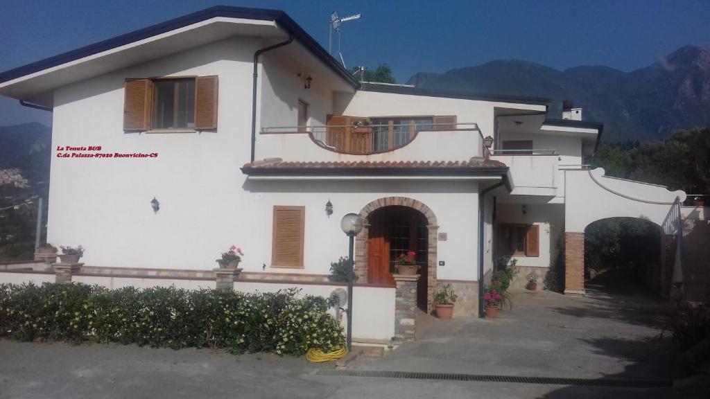 Dieses weiße Haus verfügt über eine Veranda und einen Balkon. in der Unterkunft La Tenuta B&B in Buonvicino