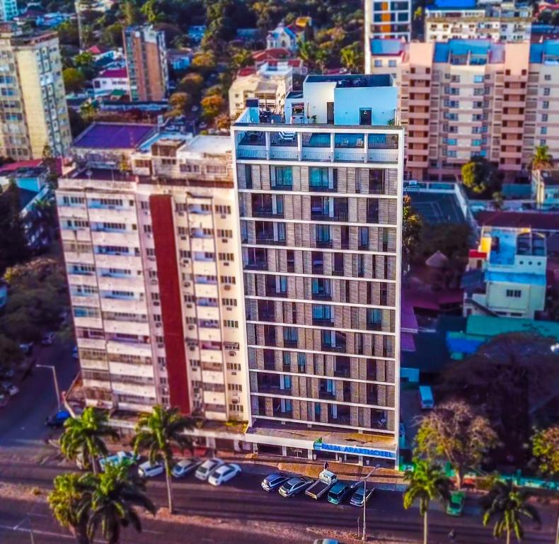 a tall building in a city with palm trees and cars at Palm Aparthotel in Maputo