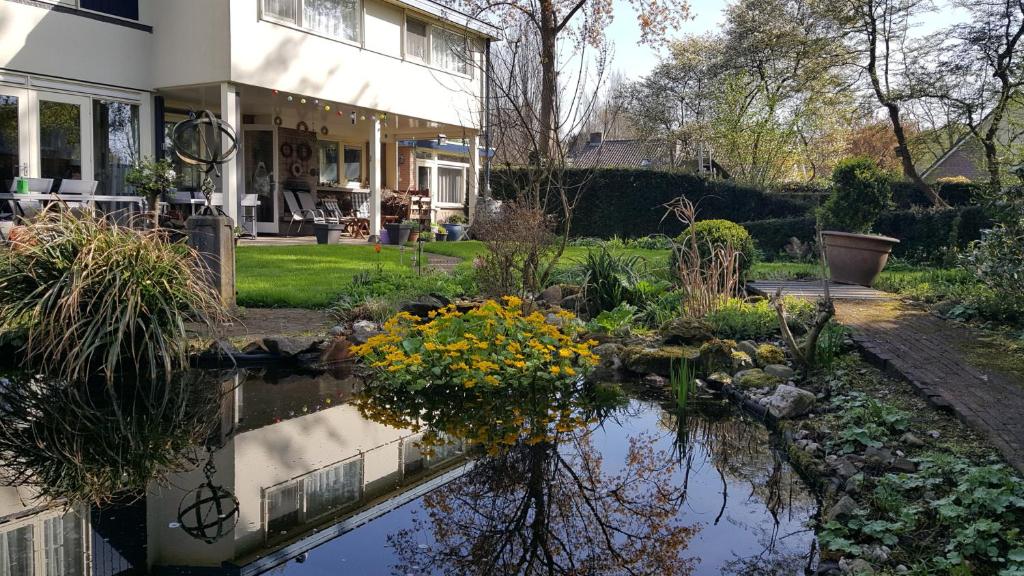 a house with a pond with flowers in it at B&B De Slaperije in Warnsveld