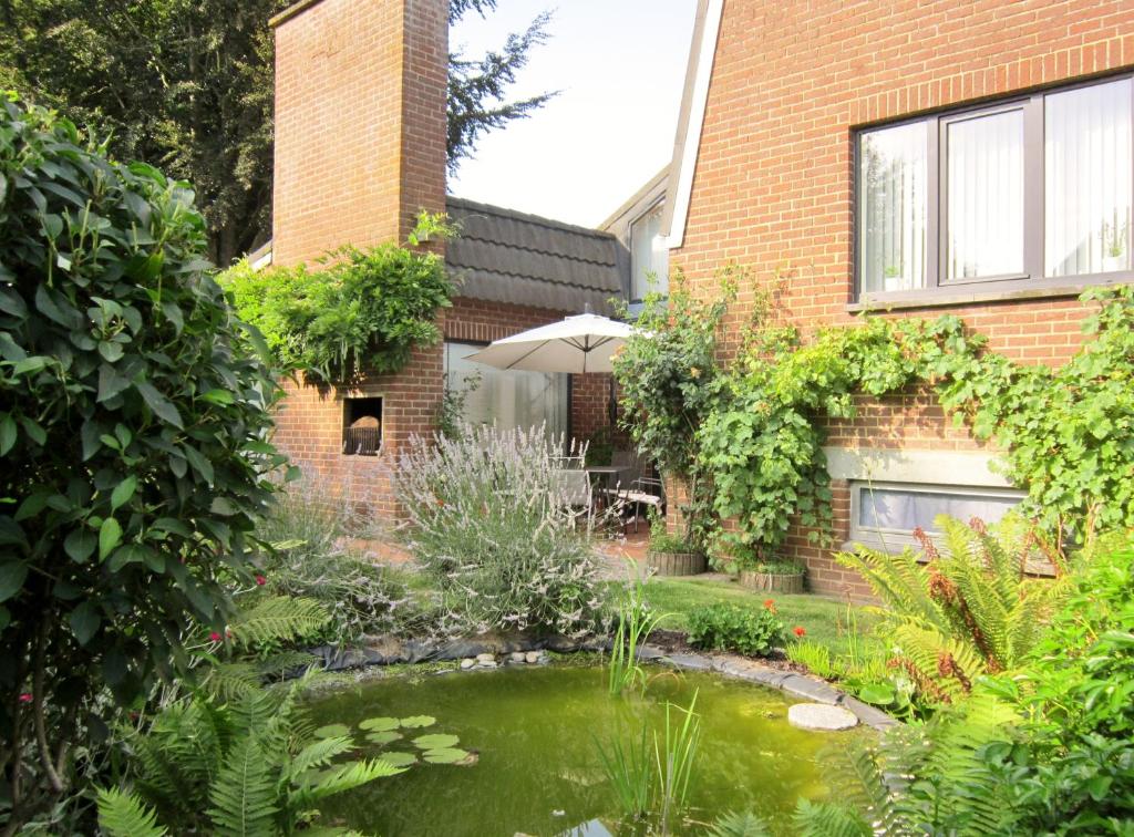 einen Garten mit einem Teich vor einem Gebäude in der Unterkunft Les Chambourlettes in Mons