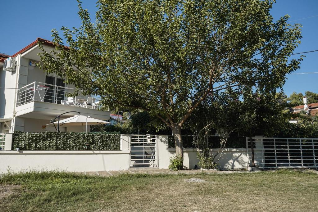 a white fence with a tree in front of a house at Nektarios Garenias Kipoupoli in Nea Kalikratia
