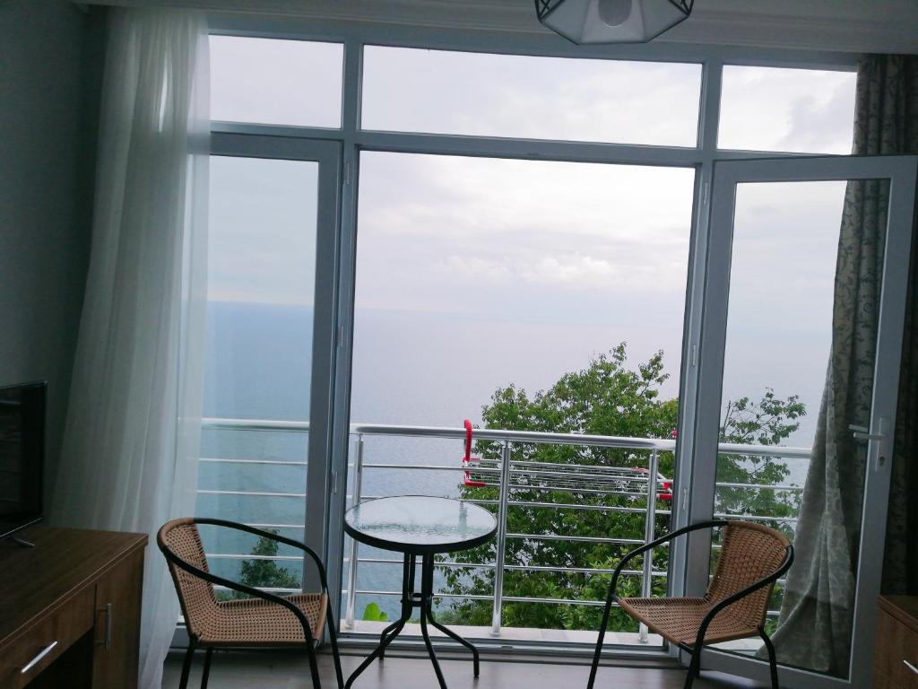 a room with a table and chairs and a large window at Albatross Kvariati Guest House in Kvariati