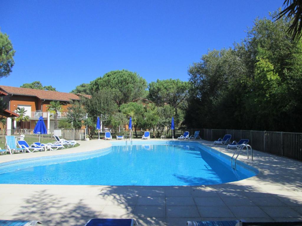 uma grande piscina com cadeiras e uma cerca em Résidence AMARINE em Capbreton