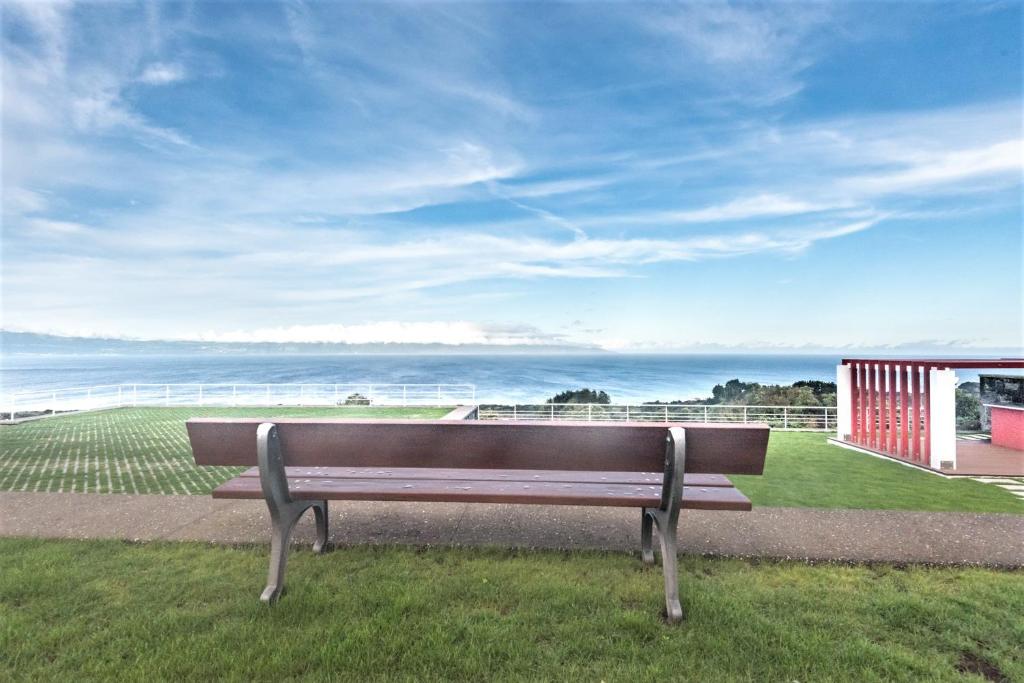 Piedade的住宿－Quinta do Basalto，坐在靠近海洋的草地上的长凳