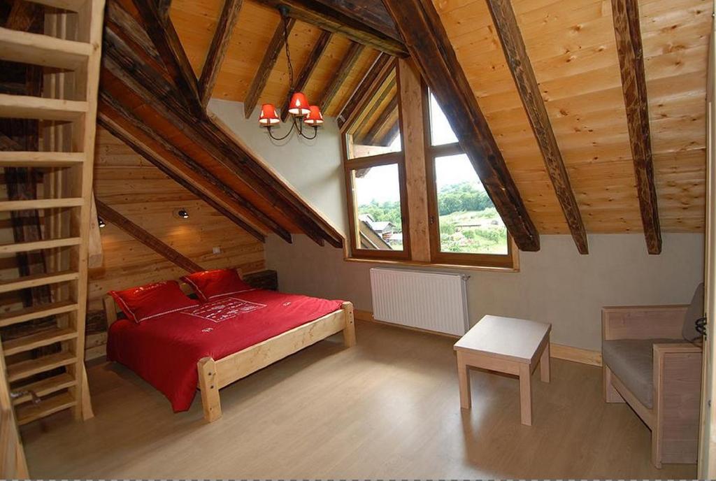 a bedroom with a red bed in a attic at La Ferme De Noémie in Mercury