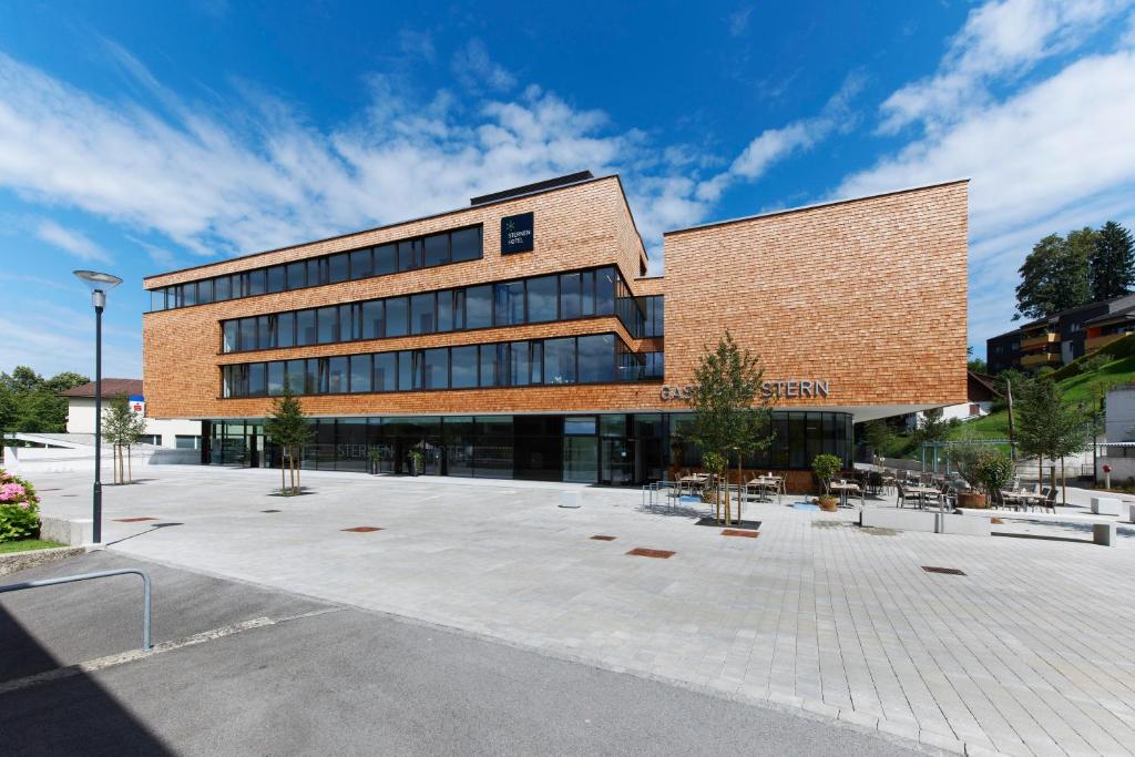 un grand bâtiment en briques avec une cour en face dans l'établissement Sternen Hotel Wolfurt, à Bregenz