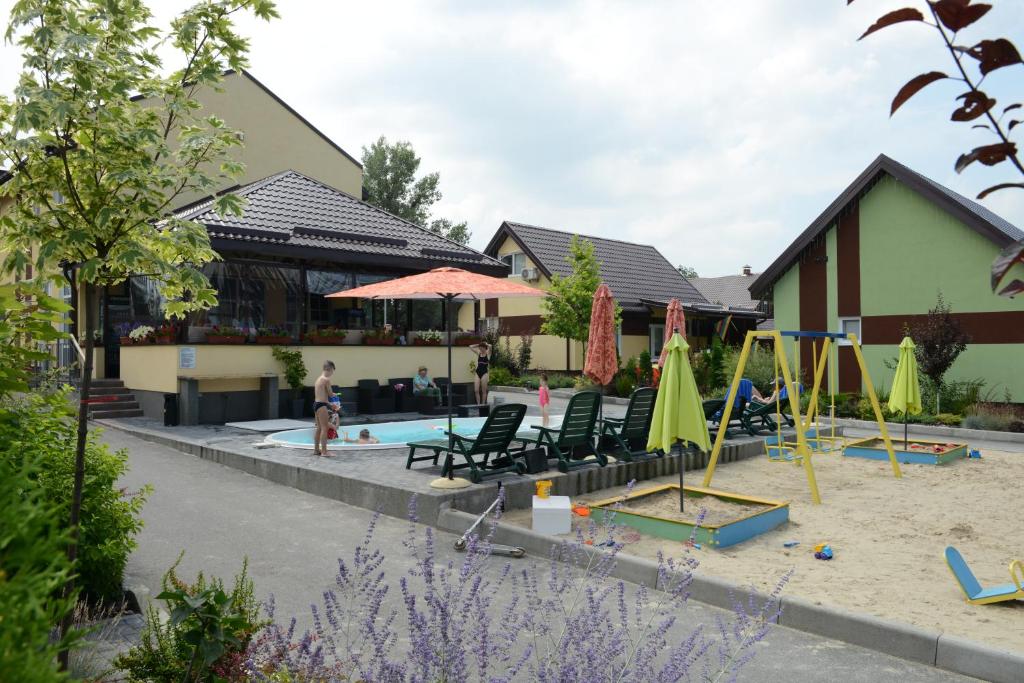 a pool with chairs and umbrellas in front of a building at Perlyna Dzvinkova in Dzvinkove