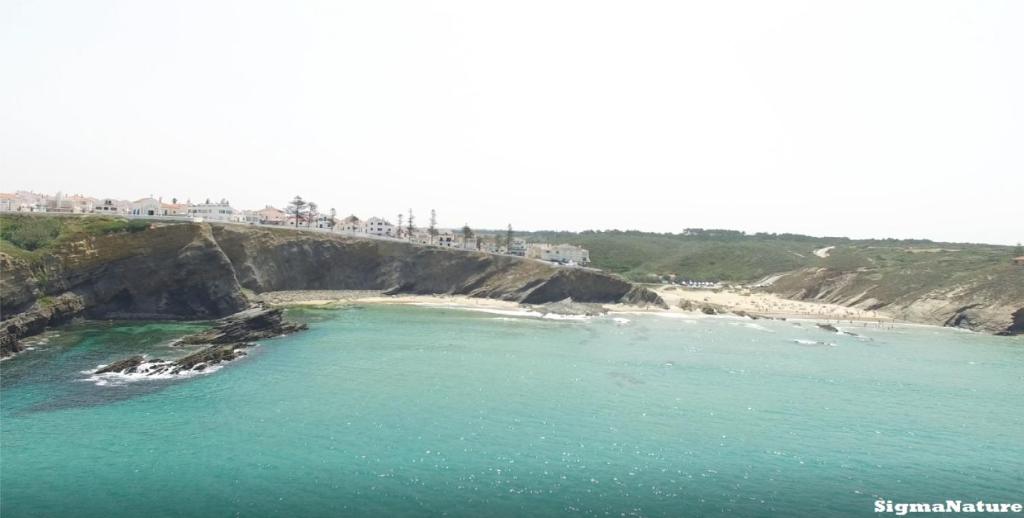 a bridge over a body of water next to a beach at Hostel Nature in Zambujeira do Mar