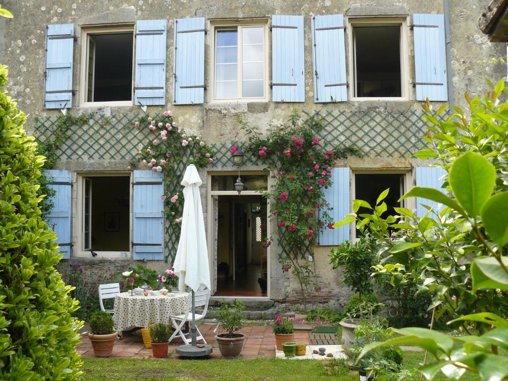 un edificio con mesa, sombrilla y flores en Le Presbytère en Labastide-dʼArmagnac