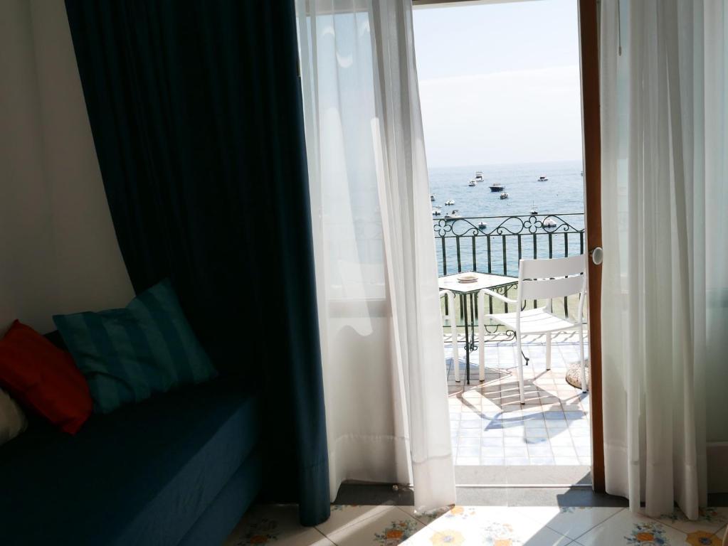 a room with a view of the ocean from a balcony at Hotel Pupetto in Positano