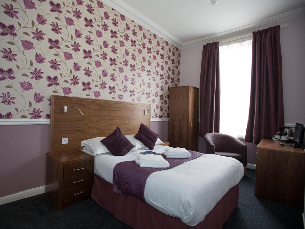 Habitación de hotel con cama y papel pintado con flores en Georgian House & Mews en York