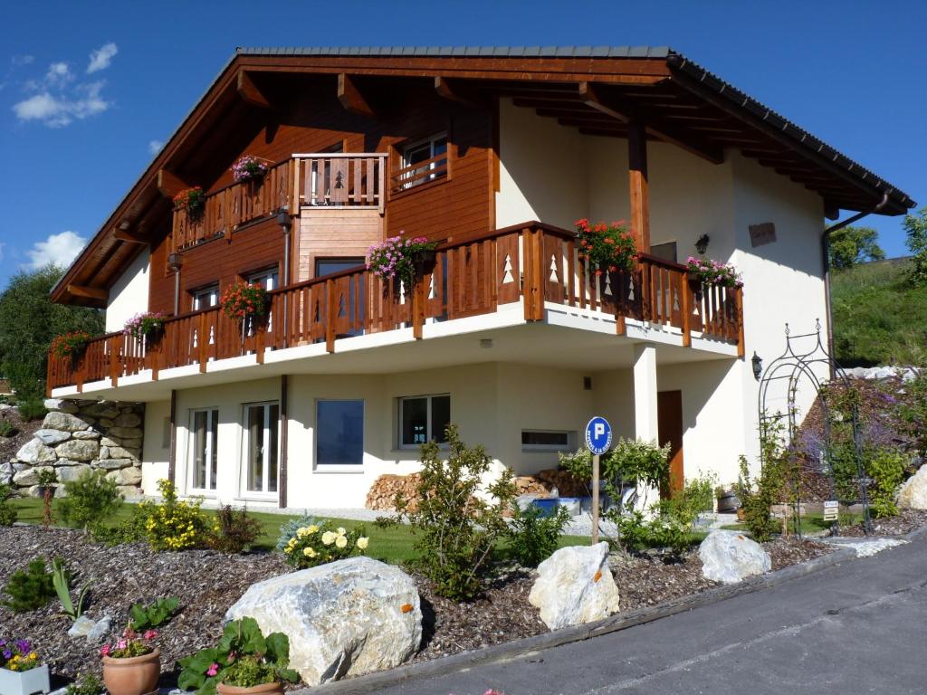 a large white house with a balcony and trees at Chalet des Alpes in Crans-Montana