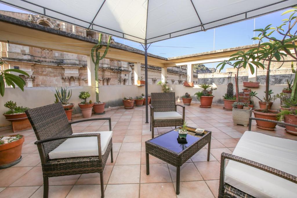 eine Terrasse mit Stühlen, Tischen und Topfpflanzen in der Unterkunft La Terrazza di Viola in Scicli