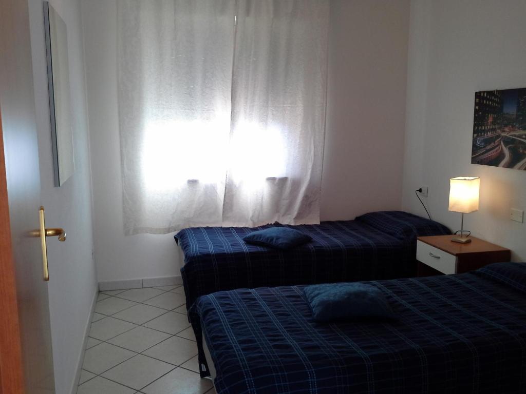 sypialnia z 2 łóżkami i oknem w obiekcie Appartamento Elegante E Panoramico Con Splendida Vista Mare w mieście Buggerru