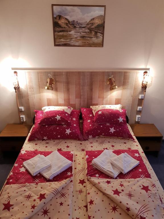 a bedroom with a bed with red sheets and pillows at Thomas Apartman Eger in Eger