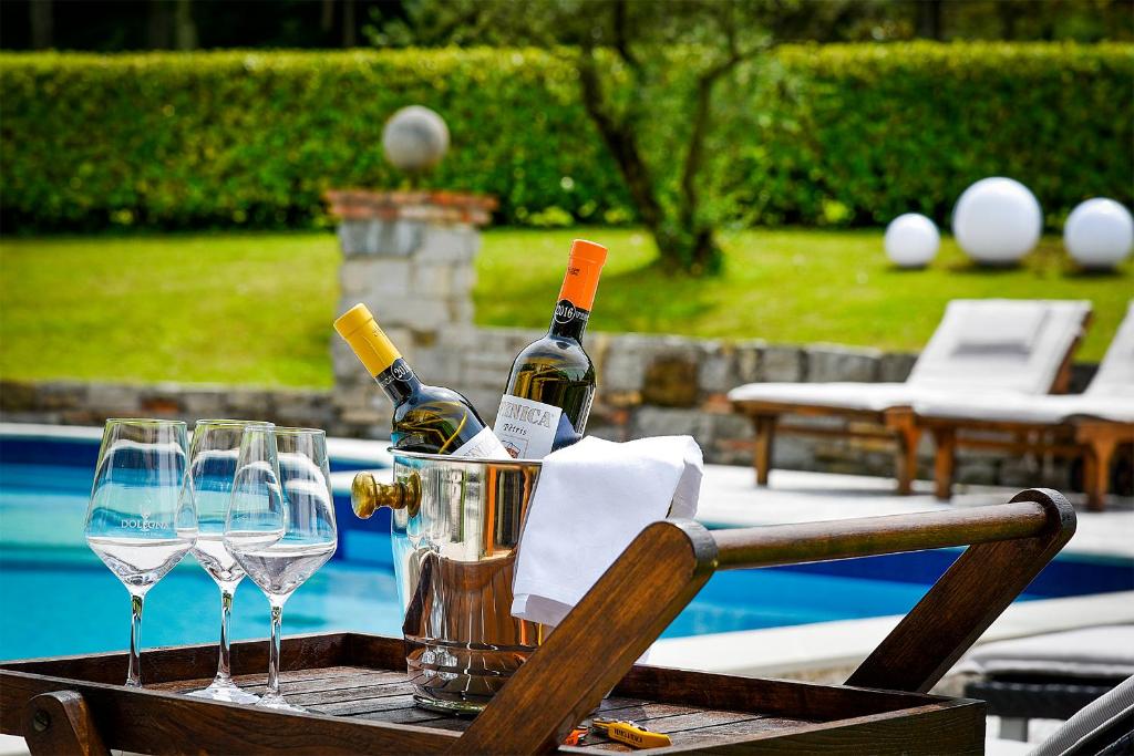 a table with wine bottles and glasses next to a pool at Venica & Venica Wine Resort in Dolegna del Collio