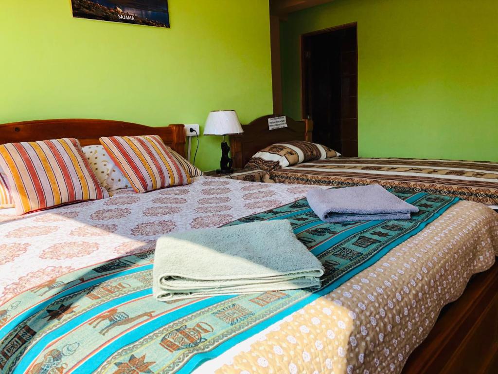 1 dormitorio con 2 camas y toallas. en Hostal Iskanwaya, en La Paz