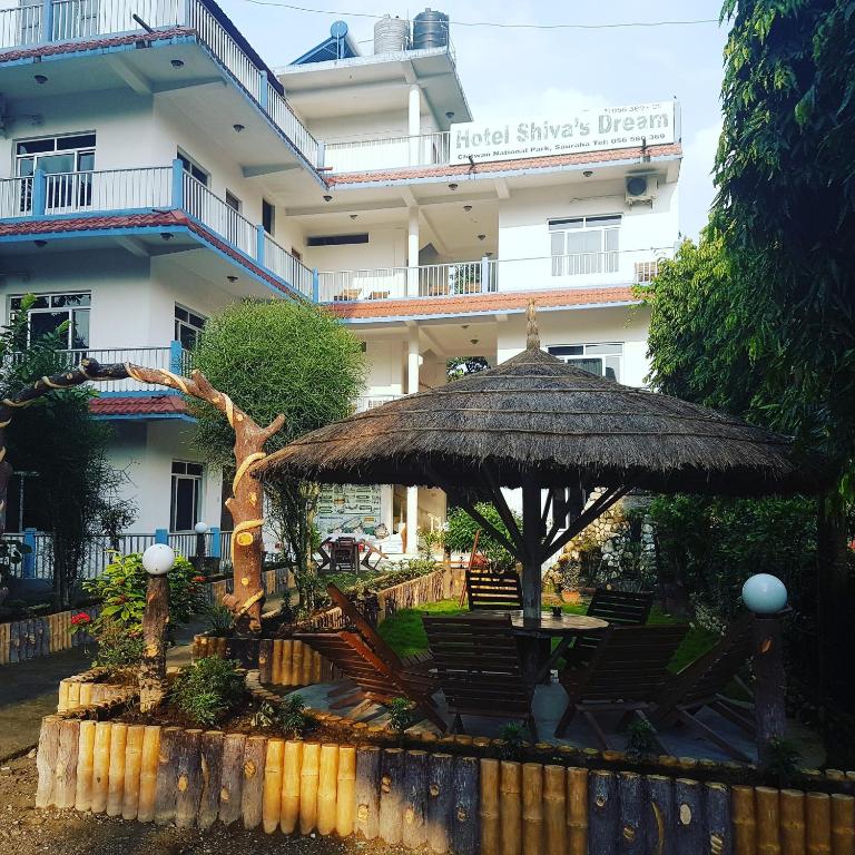 an umbrella and chairs in front of a building at Hotel Shiva's Dream in Sauraha