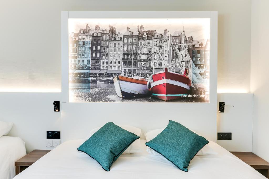 a painting of boats on a wall above a bed at Brit Hotel Caen Nord - Mémorial in Caen