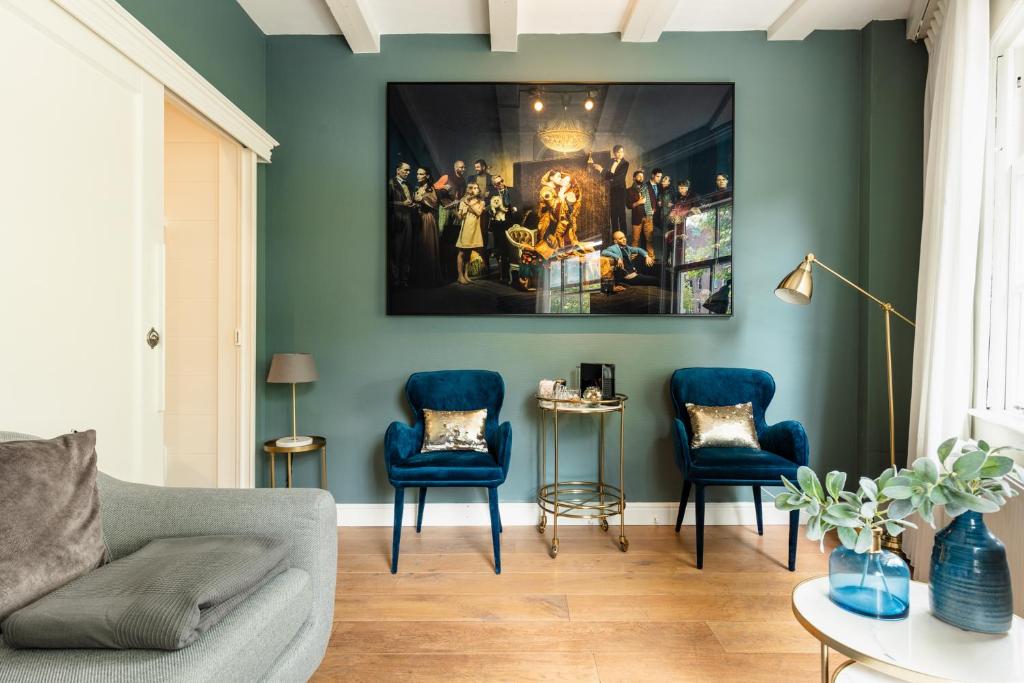 a living room with blue chairs and a painting on the wall at Canal Wow Suites Amsterdam in Amsterdam