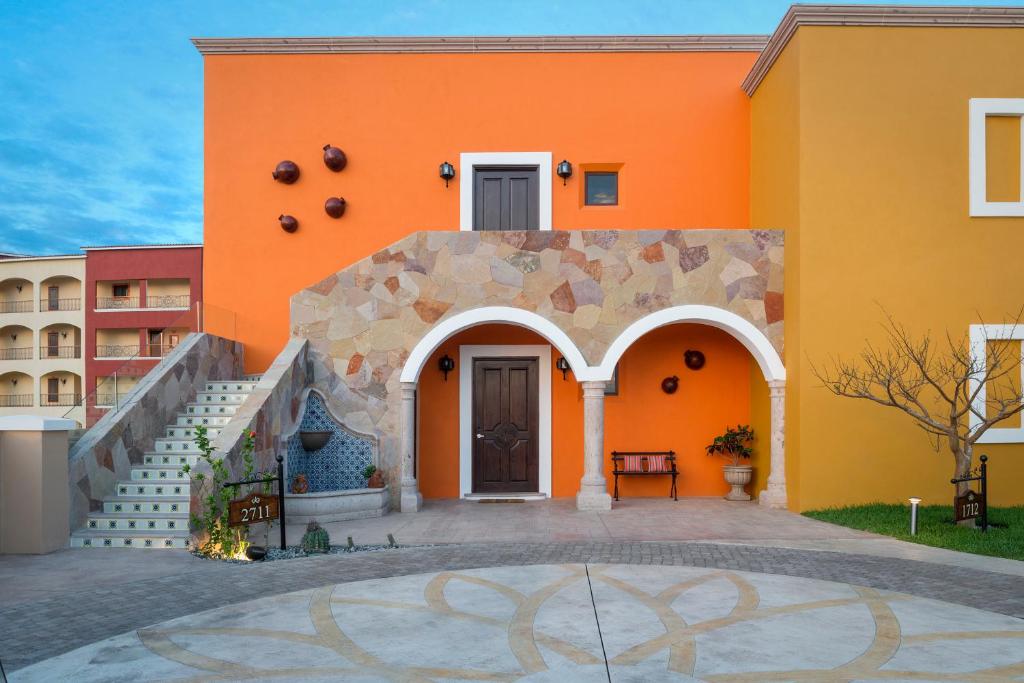 an orange building with a staircase in front of it at The Residences at Hacienda Encantada in Cabo San Lucas