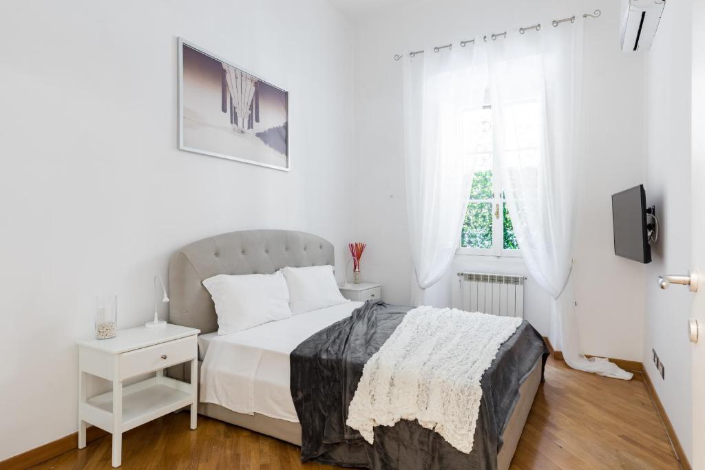 een witte slaapkamer met een bed en een raam bij A World Aparts - 32 Calabria in Rome