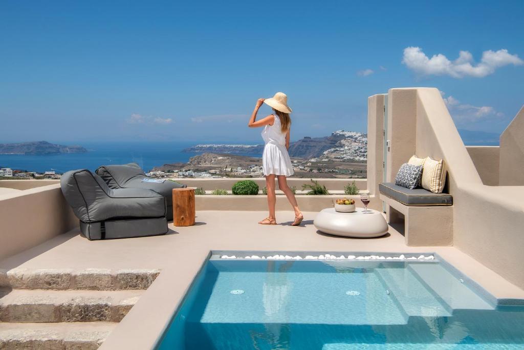a woman standing on a balcony overlooking a beach at Halcyon Days Suites in Pyrgos