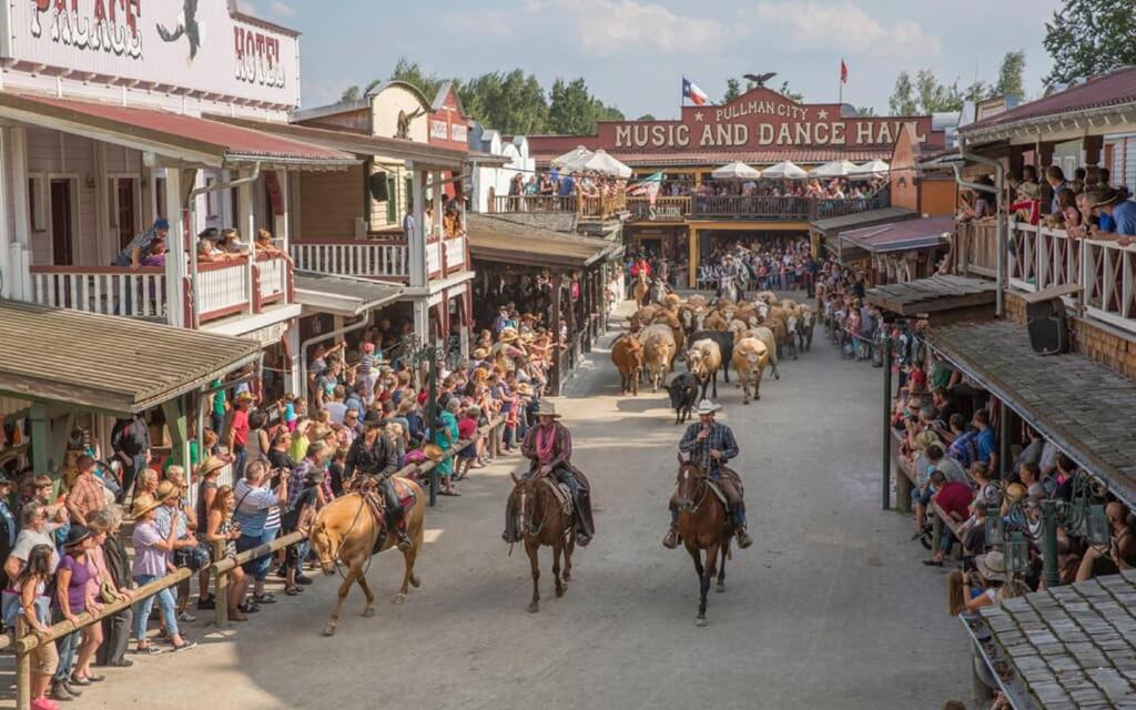 a bunch of horses and people riding down a street at Pullman City Westernstadt in Eging