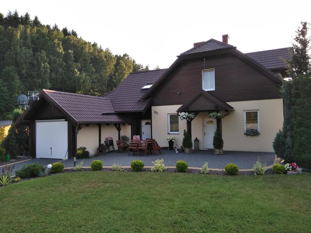 a house with a pitched roof and a yard at Apartament w Krzesznej in Krzeszna