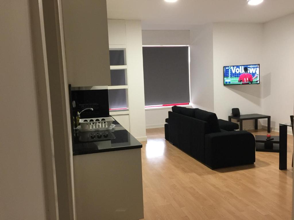 sala de estar con sofá negro y TV en Invicta House Maia, en Maia