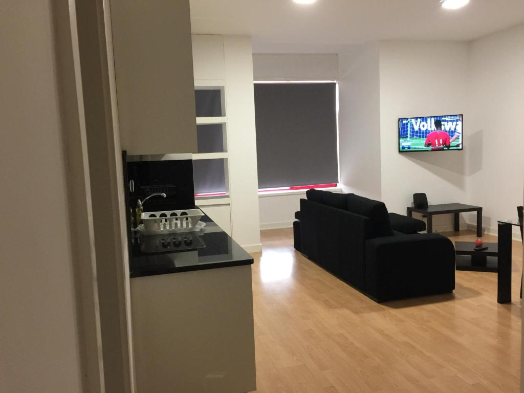 uma sala de estar com um sofá preto e uma televisão em Invicta House Maia em Maia