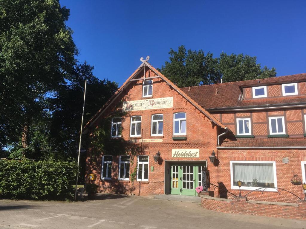 ein altes Backsteingebäude mit grüner Tür in der Unterkunft Gasthof Heidelust Pension in Undeloh