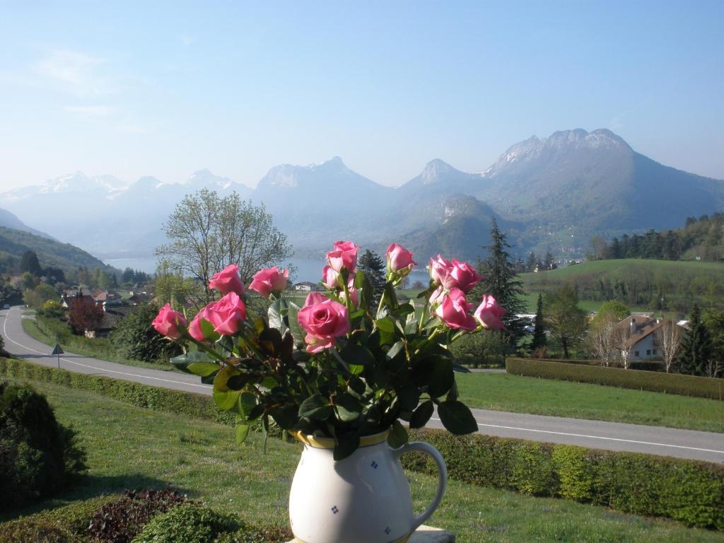 un vase blanc rempli de roses roses roses sur une route dans l'établissement Soleil Bleu 2 Etoiles, à Talloires