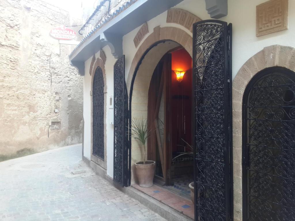 an alley with arches and a door with a potted plant at Dar Ayour appartements in Essaouira