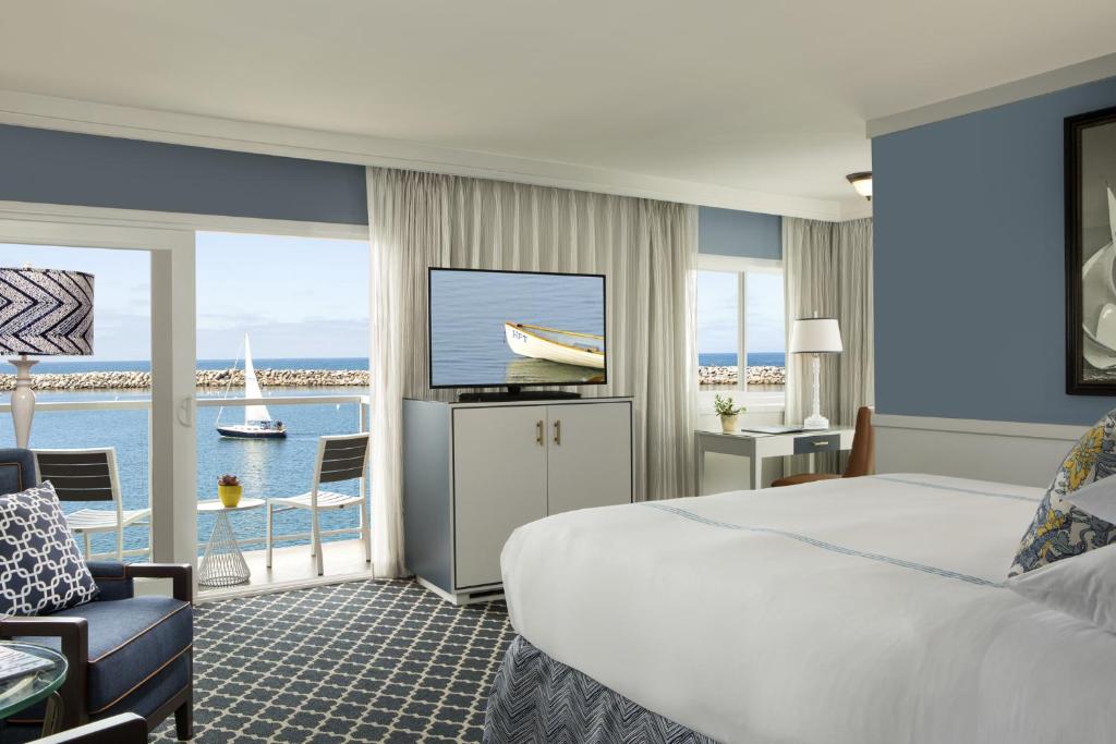 a hotel room with a bed and a view of the ocean at The Portofino Hotel & Marina, a Noble House Hotel in Redondo Beach