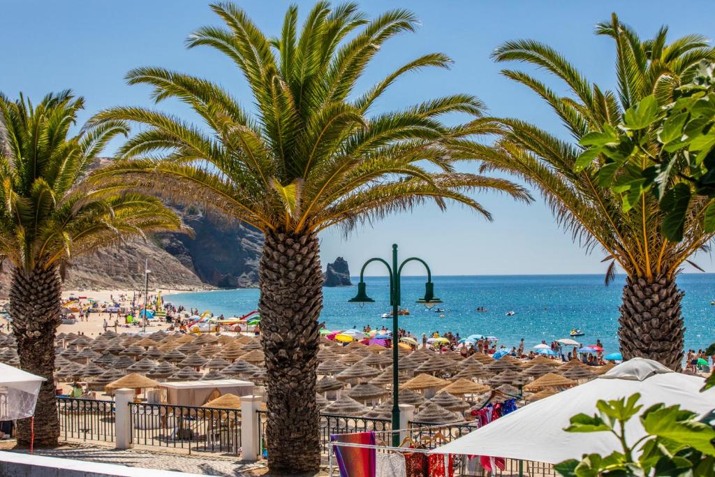 a beach with palm trees and a crowd of people at Aurora Sol in Luz