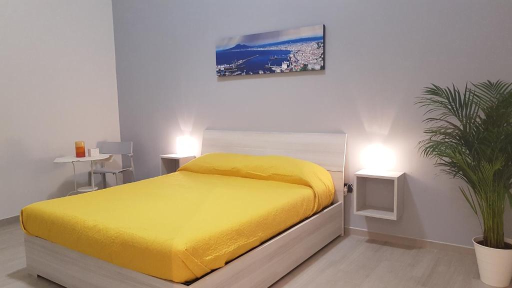 una camera con un letto giallo e una pianta di Dimora san giovanni maggiore a Napoli