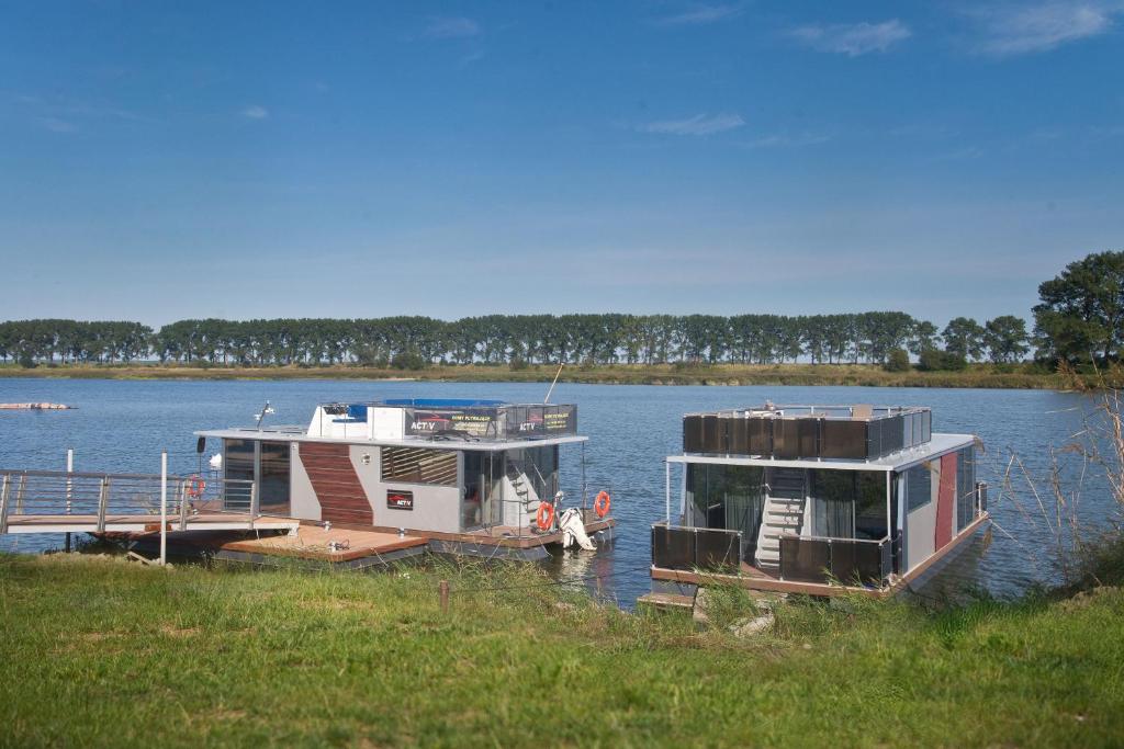 Houseboat في Błotnik: يتم رسو مركبين في مرسى على البحيرة