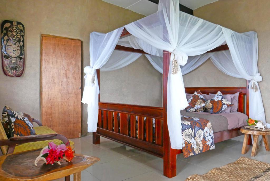 a bedroom with a canopy bed with white curtains at Paradise Taveuni in Waiyevo