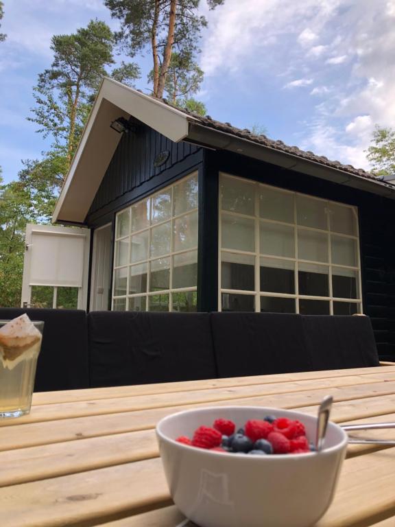 un bol de baies sur une table en bois devant une maison dans l'établissement vakantiewoning De Lutte, à De Lutte