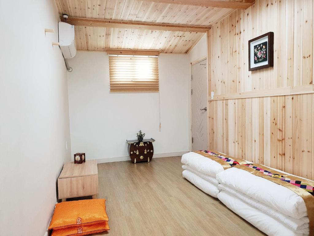una camera con due letti bianchi in una stanza con pareti in legno di Dal Garam Guesthouse - 외국인 전용 a Gangneung