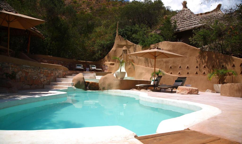 Maji Moto阿拉罗山林小屋的后院的游泳池,带遮阳伞