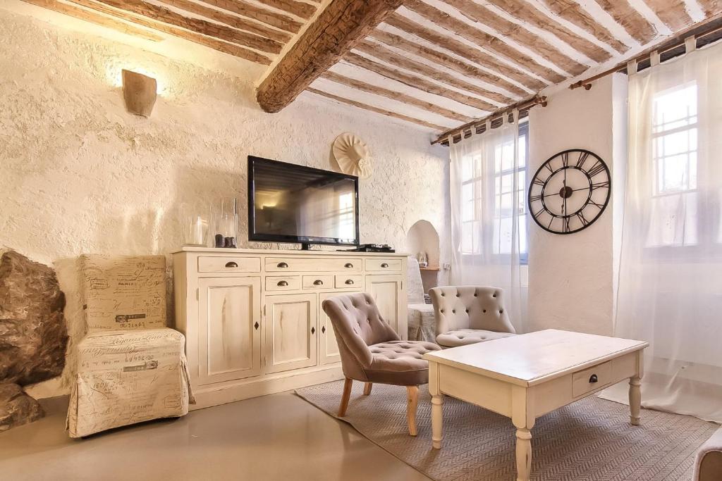 ein Wohnzimmer mit einem TV und einem Tisch in der Unterkunft Bijou Apartment in Safranier - Old Town Antibes in Antibes
