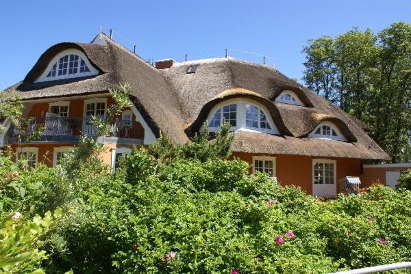 ein Haus mit einem Strohdach und einigen Büschen in der Unterkunft Hotel Residenz Rennhack in Prerow