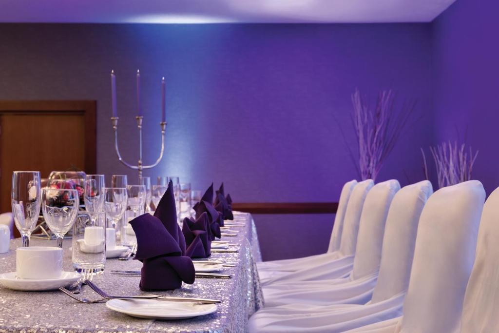 a long table with white chairs and a purple wall at Coast Edmonton Plaza Hotel by APA in Edmonton