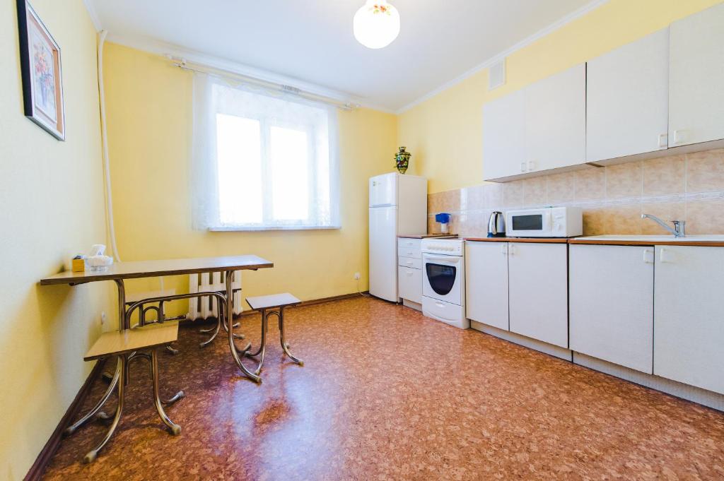 a kitchen with white cabinets and a table and a sink at Dekabrist Apartment at leningradskaya 24 in Chita