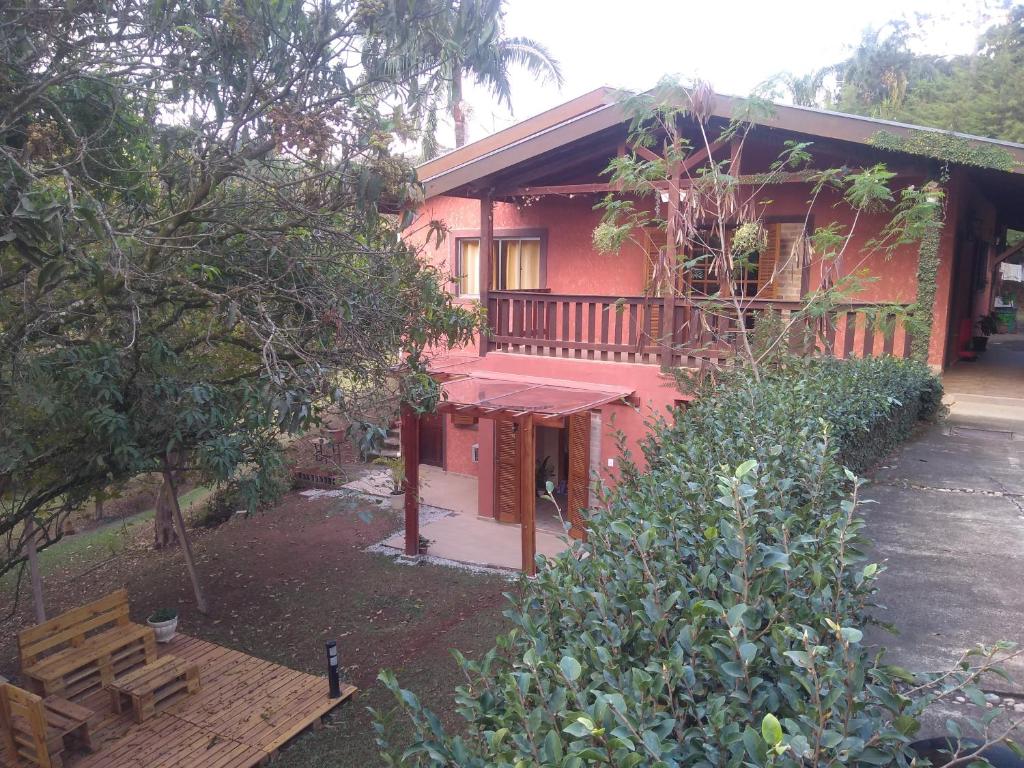 een rood huis met een veranda en een houten terras bij Recanto Pôr do Sol in Campo Limpo