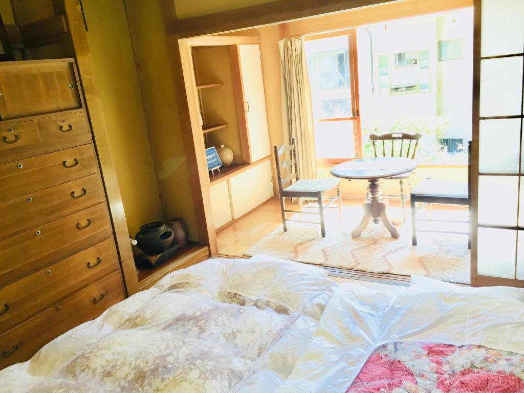 a bedroom with a bed and a table and chairs at Vanguard Backpackers in Sagamihara