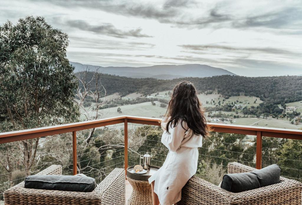 una mujer sentada en un balcón con vistas a las montañas en Kangaroo Ridge Retreat en Healesville
